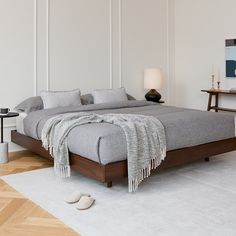 a large bed sitting on top of a wooden floor next to a table with a lamp