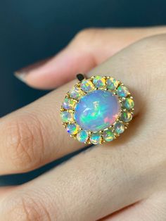 RING DETAILS: ✪Design: Gold ring ✪Gemstone: Opal ✪Gemstone shape: Cabochon oval ✪Gemstone size: Center stone: 12x10mm Oval, side stones: 3mm round ✪Setting type: Cluster ✪Metal type: 14k solid yellow gold (also available in white and rose gold, please select at checkout) ✪Total ring weight: 7 grams ✪Metal finish: Smooth shiny Choose your ring size from drop down menu and if you need any other preferred ring size please contact us. QUALITY OF MATERIALS: Metal: Most of our jewelry at JewelryMansio Yellow Gold Cluster Jewelry With Halo Setting, Yellow Gold Cluster Rings With Multi-stone, Cluster Birthstone Ring Fine Jewelry, Fine Jewelry Multi-stone Round Cut Opal Ring, Fine Jewelry Opal Ring With Multi-stone Round Cut, Diamond Multi-stone Opal Ring, Cluster Multi-stone Opal Ring For Anniversary, Fine Jewelry With Halo Cluster, 14k Gold Cluster Ring With Accent Stones