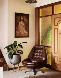 a brown chair sitting in front of a doorway next to a painting on the wall