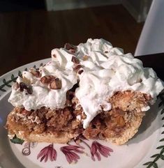 a piece of cake on a plate with whipped cream and pecans around the edges