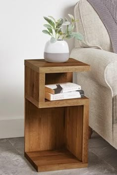 a small wooden table with two books on it and a potted plant in the corner