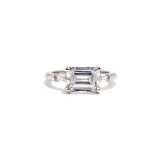 an emerald cut diamond ring with three baguets on the band and side stones