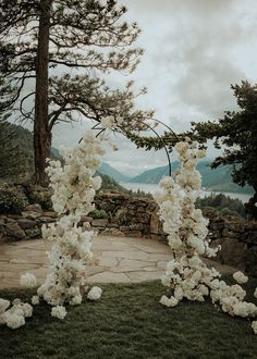 an outdoor ceremony with white flowers and greenery on the ground, overlooking mountains in the distance