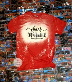 a red shirt with the words chaos coordinating on it is hanging against a brick wall