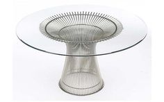 a glass and metal table with a circular base on the top, in front of a white background