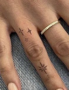 two fingers with tattoos on them and one has a star tattoo on the middle finger