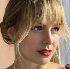 a woman with blonde hair and blue eyes is looking at the camera while wearing red lipstick