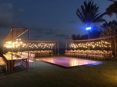 an outdoor wedding setup at night with lights on the dance floor and tables set up