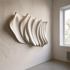 a group of white wavy shapes hanging on the side of a wall next to a window