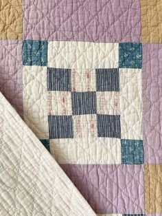 a close up of a quilt on top of a bed with purple and blue squares