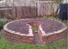 a brick fire pit in the middle of a yard