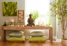 a buddha statue sitting on top of a wooden table in front of a window filled with candles