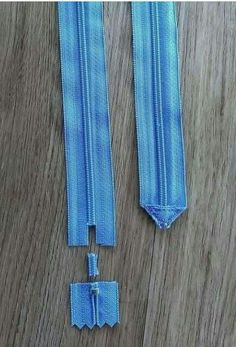 two blue zippers are laying on a wood floor with one open and the other closed