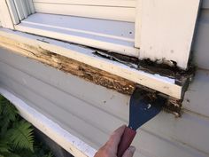 a person holding a paint brush in front of a window sill that has been gutted