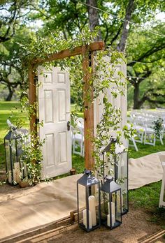 an outdoor ceremony set up with white chairs and greenery