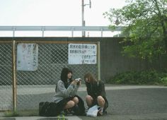 two women sitting on the ground taking pictures