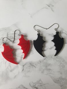 A pair of acrylic bat or dragon wings attached to titanium french hooks - they're hypoallergenic and nickle free, so perfect for anybody that suffers with metal sensitivities or nickel allergies Available in red and matte black, the red have black vein details, these are also present on the black however they're very difficult to photograph due to the same colouring The wings are laser cut from acrylic sheet and measure 3mm thick, and measure 5cm in full length I have photographed them beside a Black Earrings For Halloween Cosplay, Black Halloween Cosplay Earrings, Black Gothic Earrings For Cosplay, Crochet Bat, Goth Accessories, Nickel Allergy, Gothic Gifts, Alternative Jewelry, Gothic Earrings