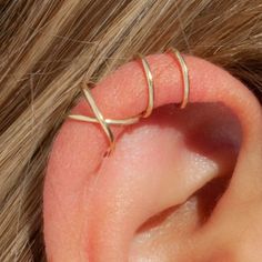 a woman's ear with two thin gold rings on top of her ear and one behind the ear