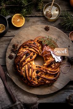 a round pastry sitting on top of a wooden table next to oranges and pine cones