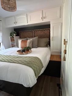 a bed with white and green sheets in a bedroom next to a doorway that leads into another room