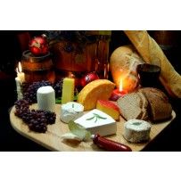 an assortment of cheeses and bread on a cutting board with candles in the background