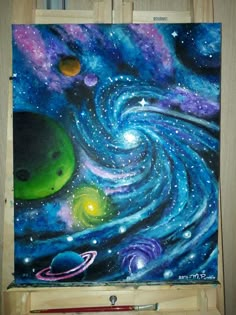 an easel with a painting on it that has planets and stars painted on it