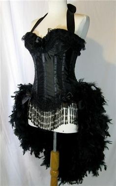 a black corset with feathers on it is sitting on a mannequin