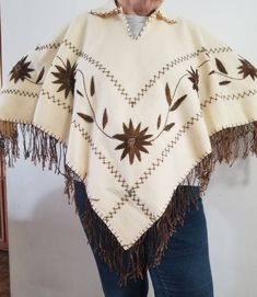 "Beautiful  hand made vintage bone colored wool pull over/poncho with embroidered  flowers and fringe. Embroidery goes around the entire poncho. With a Cute little bone replica fastener at the neck line.  the bottom fringe is not perfect, has a few frazzles (as pictured) over all great shape One size fits most ! neck opening when buttoned is 7\"	in stock	105.00 USD	91.35 USD	0.00 USD	Clothing > Women's Clothing > Ponchos
https://i.etsystatic.com/38666515/r/il/42cf57/4620602276/il_fullxfull.46206 Traditional White Poncho For Fall, Cream Bohemian Shawl For Fall, Cream Bohemian Poncho For Fall, Winter Festival Embroidered Poncho, Traditional Fringe Poncho For Fall, White Vintage Shawl For Winter, Bohemian Cream Shawl Poncho, Embroidered One-size Poncho For Fall, Traditional Fall Poncho With Fringe