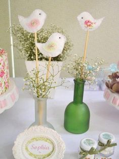 two small birds are sitting on top of some flowers in vases and cake pops