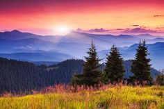 the sun is setting in the mountains with tall grass and trees on the hillside below