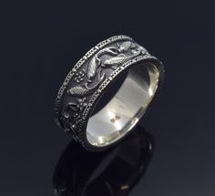 a wedding ring with an intricate design on the outside and inside, sitting on a black surface