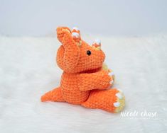 an orange crocheted stuffed animal sitting on top of a white fur covered floor