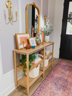 an entryway with a mirror, potted plant and other items on the shelf