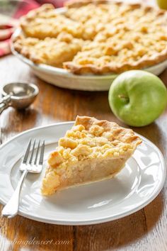 a slice of pie on a plate with an apple in the background