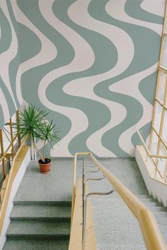 an indoor stair case with a potted plant next to it and painted waves on the wall