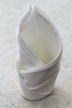 three folded napkins sitting on top of each other in a cup holder with white fabric