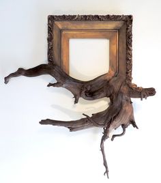 a wooden frame hanging on the wall next to a dead tree branch and another piece of wood