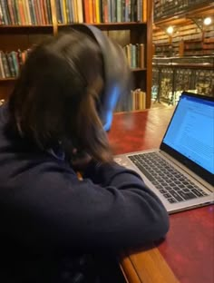 a person sitting in front of a laptop computer on a table with books behind them