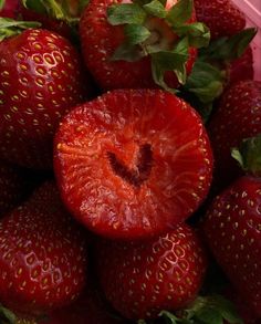 a pile of ripe strawberries sitting on top of each other in a pink container