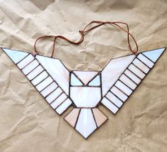 a stained glass bird decoration hanging from a string on a piece of brown parchment paper