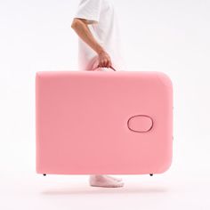 a man carrying a pink piece of luggage with his hands on the top of it