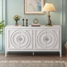 a white sideboard with two doors and a lamp next to it in a living room