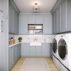 a kitchen with gray cabinets and white counter tops, including a washer and dryer