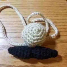 a small crocheted object sitting on top of a wooden table next to a string