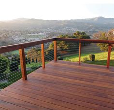 a wooden deck with metal railing overlooking a valley