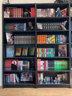 a book shelf filled with lots of books on top of wooden floor next to a wall