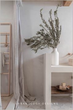 a white vase filled with green plants on top of a counter next to a shower