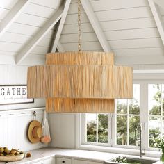 a kitchen with white cabinets and a large bamboo light fixture hanging from the ceiling above it