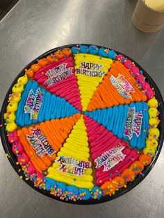 a birthday cake decorated with candy and candies on a metal countertop next to a cup