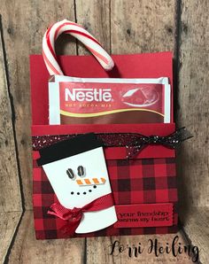 a red and black paper bag with a snowman on the front, candy bar in the back